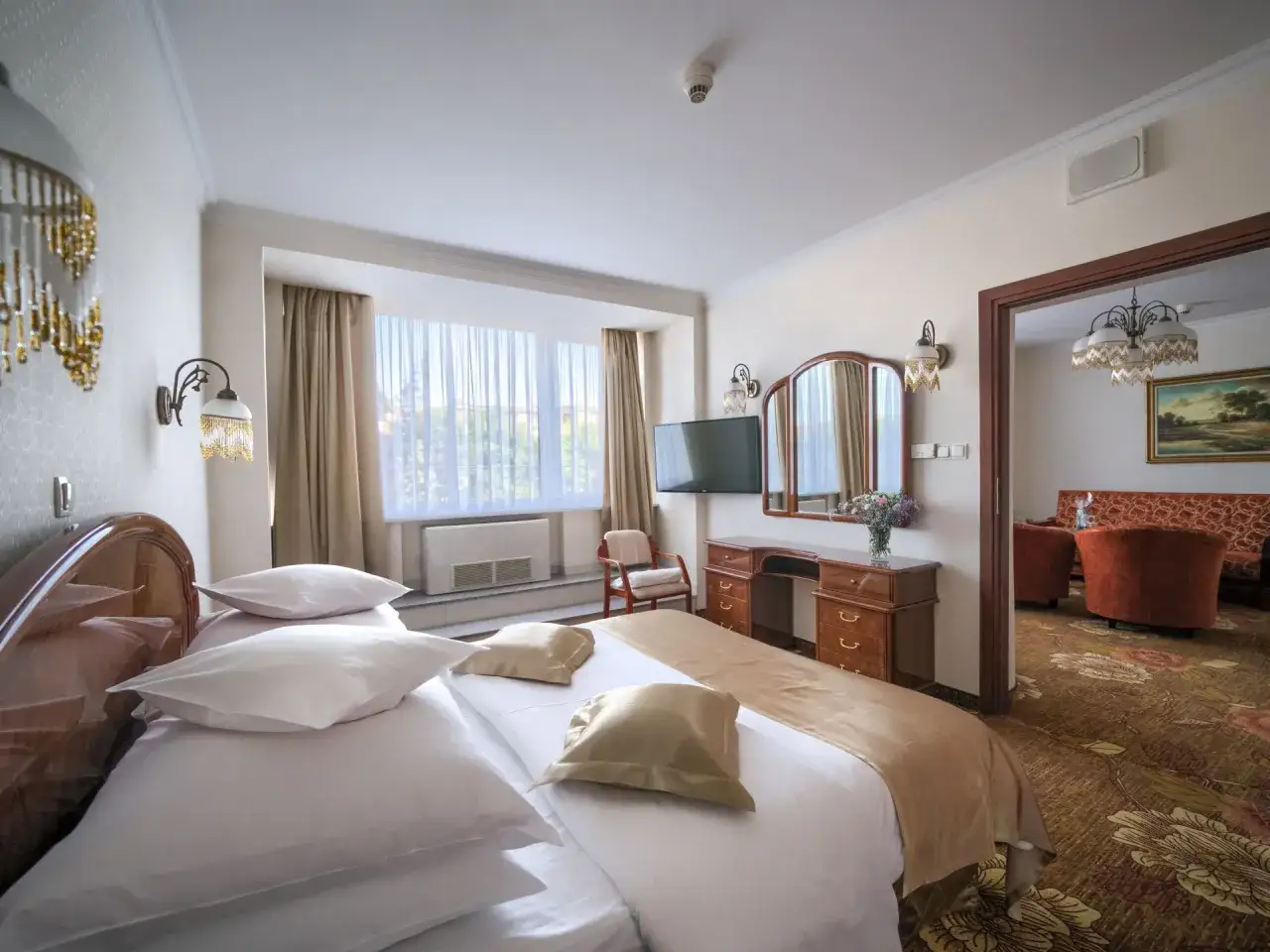 Przytulny pokój hotelowy w Białymstoku z dużym łóżkiem, toaletką i widokiem na salon.