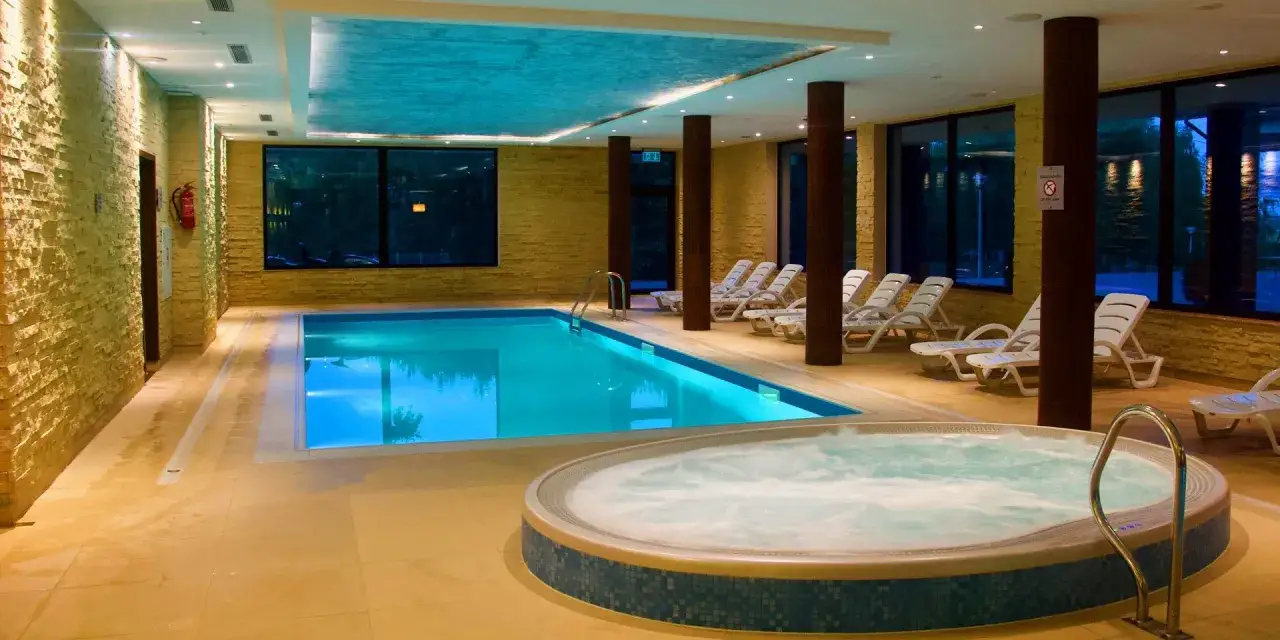 Relaks w mikołajki hotel z basenem i jacuzzi. Czysta woda, leżaki i kamienne ściany tworzą przytulną atmosferę.