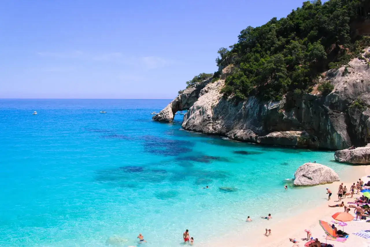 Cala Goloritze: turkusowa woda, skaliste klify i plażowicze cieszący się słońcem.