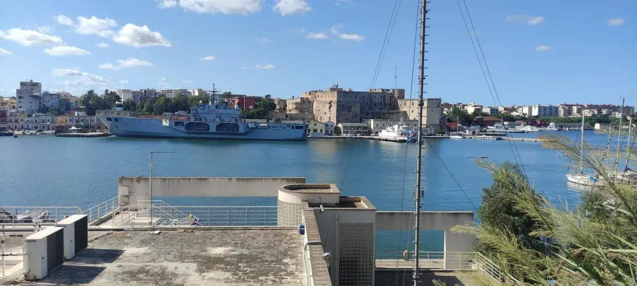Widok na port w Brindisi: imponujący zamek, okręt wojenny i żaglówki. Co zobaczyć w Brindisi?