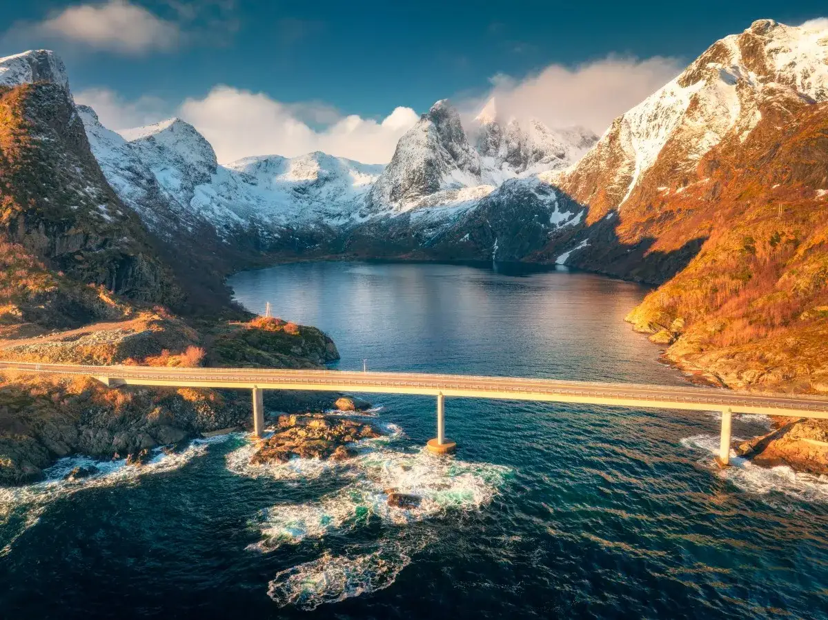Most piękny widok na fiordy Norwegii, z ośnieżonymi górami i błękitną wodą.