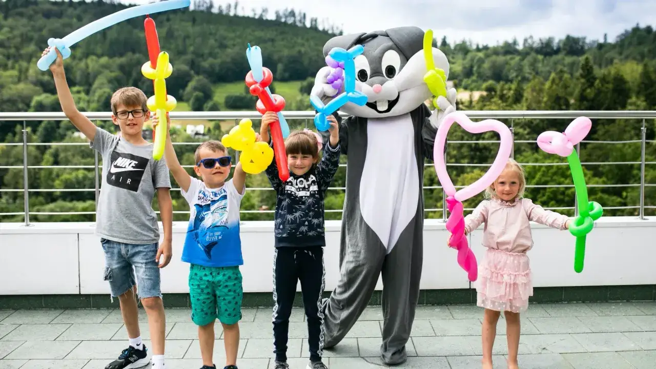 Dzieci z animatorami w strojach postaci z balonami w rękach. Idealne hotele z animacjami dla dzieci.
