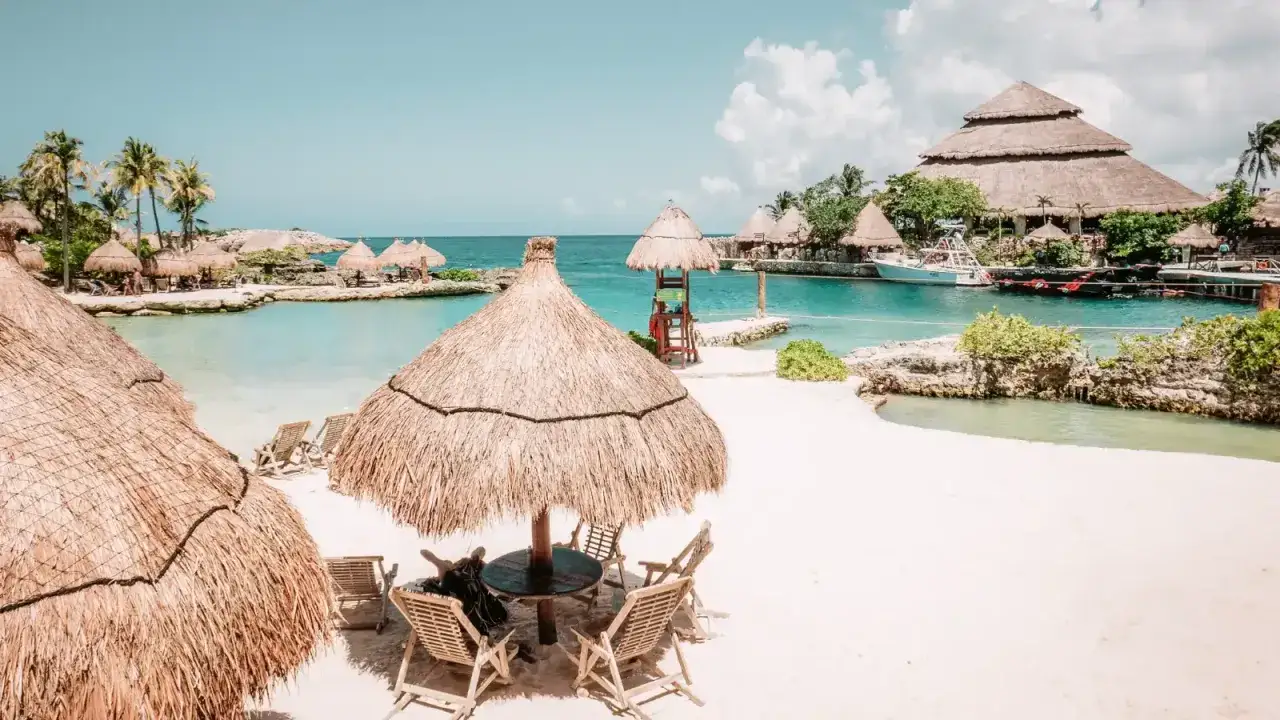 Idealne miejsce, gdzie na wakacje w październiku: piaszczysta plaża, turkusowa woda, palmy i słomiane parasole.