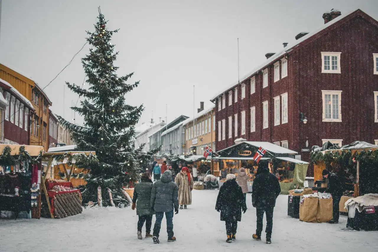 Świąteczny jarmark w Norwegii, z choinką i ludźmi w zimowych ubraniach. Ciekawe ciekawostki o Norwegii można odkryć, spacerując takimi uliczkami.
