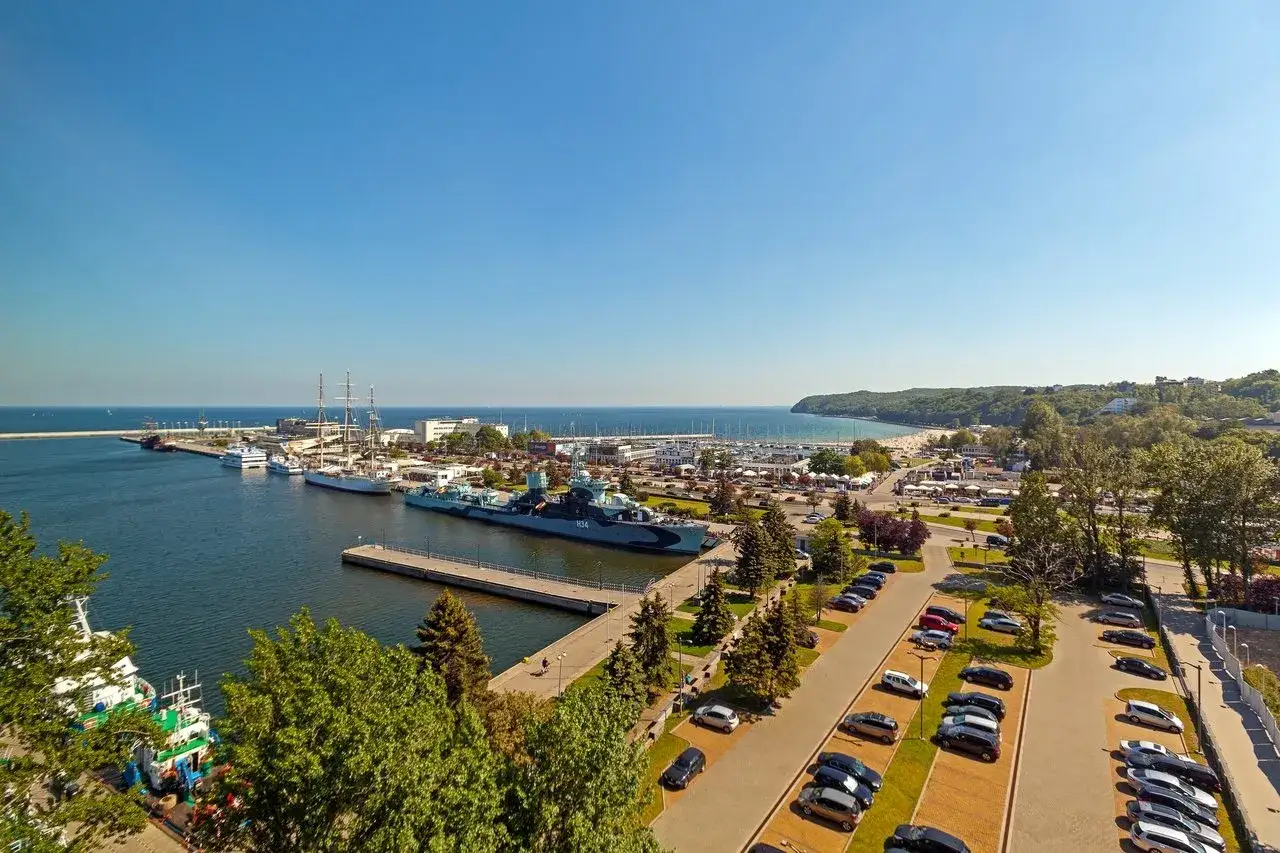 Widok na port w Gdyni z żaglowcami i okrętem ORP Błyskawica. W tle plaża i wzgórza. Idealne miejsce na pobyt w courtyard hotels Gdynia.