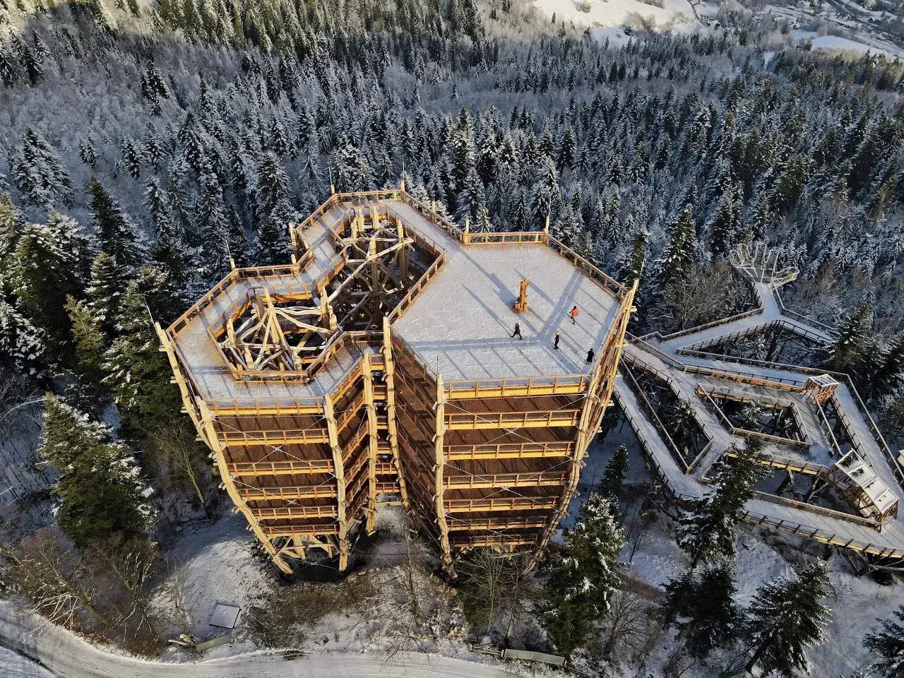 Drewniany taras widokowy w Wiśle, otoczony ośnieżonym lasem, zaprasza do podziwiania zimowej panoramy.