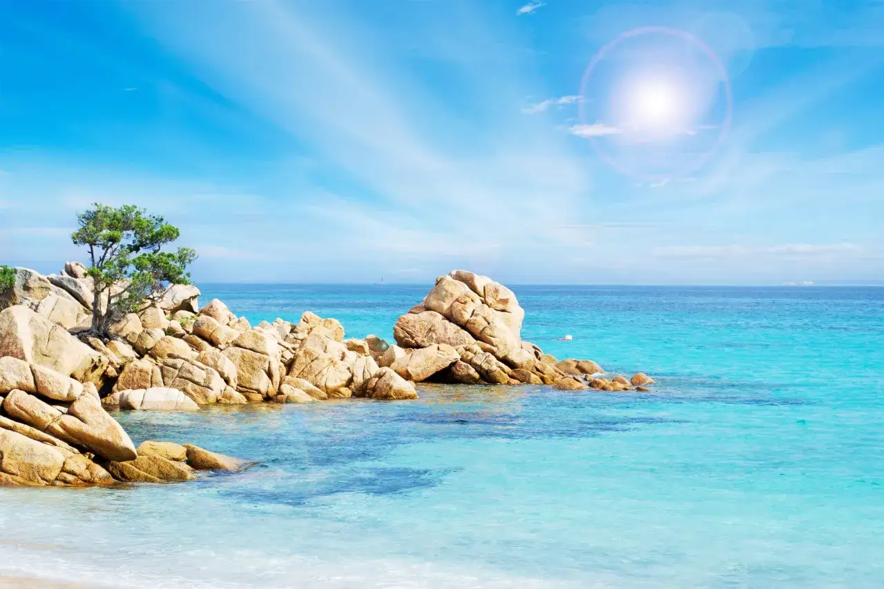 Skały i turkusowa woda na Costa Smeralda. Słońce odbija się w krystalicznie czystej wodzie, tworząc magiczny widok.