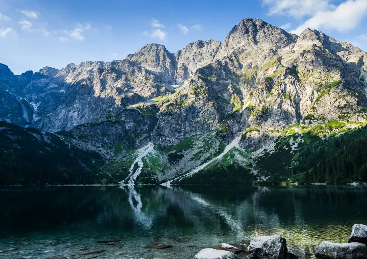 Majestatyczne góry odbijają się w spokojnej tafli jeziora. Widok na wejście na Morskie Oko zapiera dech w piersiach.