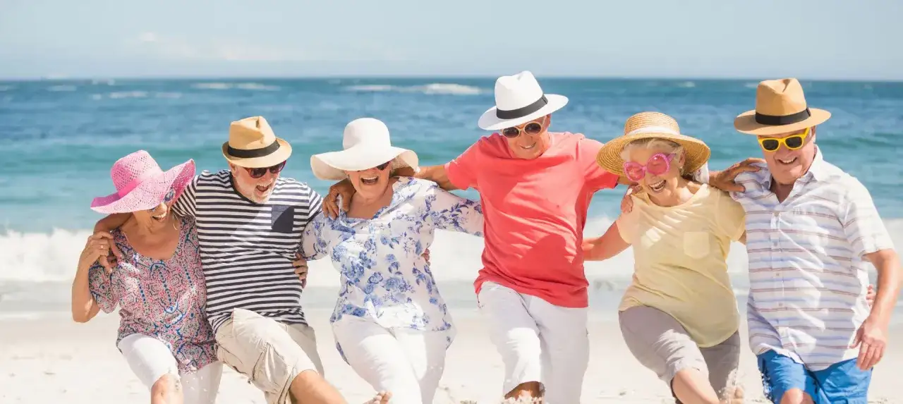 Szczęśliwi seniorzy na plaży, cieszący się wakacjami. Idealne wczasy dla seniora 7 dniowe, pełne słońca i radości.