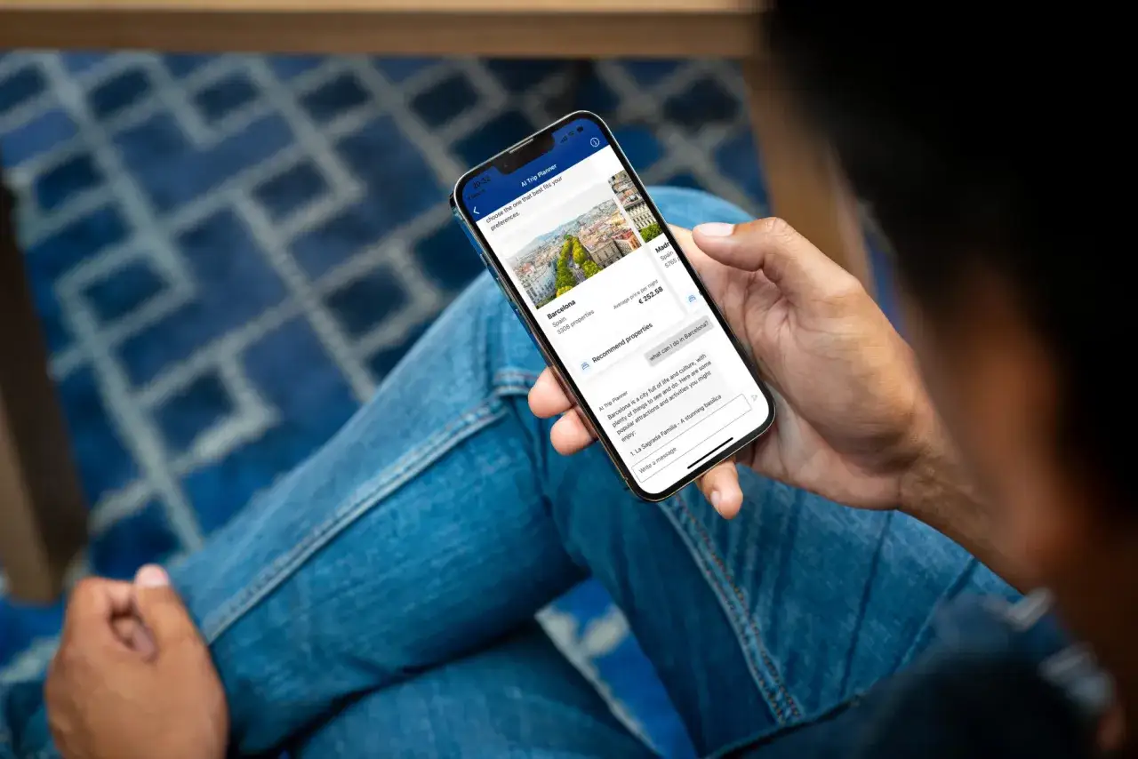 Dłoń trzyma smartfon z aplikacją podróżniczą. Widok Barcelony, ceny noclegu i sugestie atrakcji. Idealne dla globtrotera planującego wyjazd.