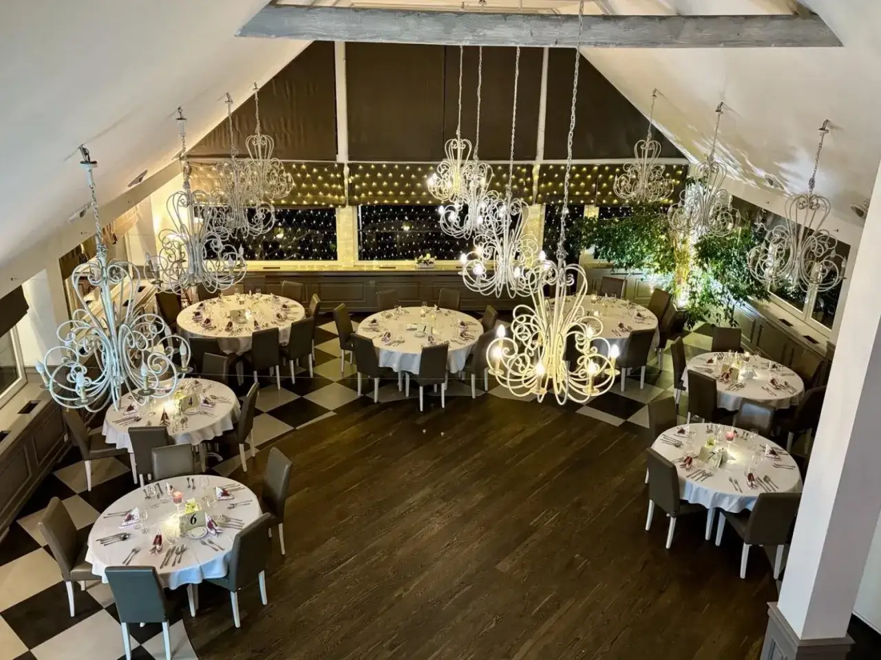 Elegancka sala bankietowa z okrągłymi stołami, ozdobiona kryształowymi żyrandolami. Idealne miejsce, gdzie dobrze zjeść w Szczytnie.