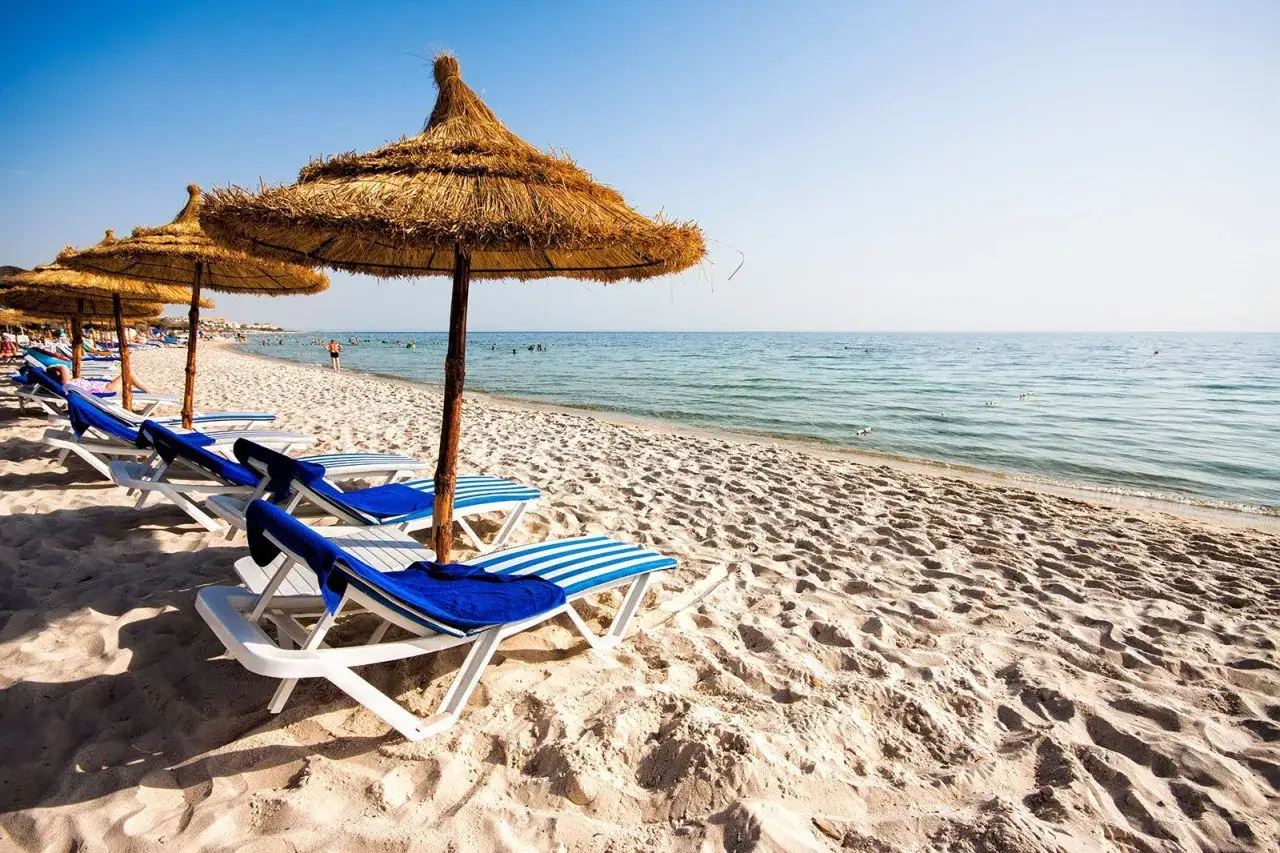 Piękne tunezyjskie plaże z leżakami i słomianymi parasolami, gotowe na turystów.