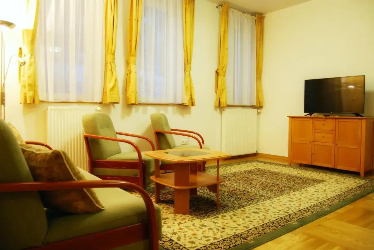 Przytulny salon z wygodnymi fotelami i stolikiem. Idealne miejsce na relaks po dniu pełnym wrażeń w Wiśle. Zameczek Wisła noclegi oferuje komfortowe pokoje.
