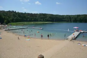 Słoneczny dzień nad jeziorem płotki. Ludzie kąpią się, pływają na dmuchanych zabawkach i odpoczywają na piaszczystej plaży.