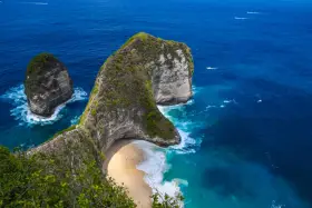 Spektakularny widok na Kelingking Beach z klifu, turkusowa woda, białe fale i zielone wzgórza.