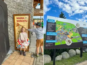 Dzieci mierzą wzrost przy tablicy "Miarka Wzrostu" w Białce Tatrzańskiej, gdzie latem czekają liczne atrakcje wodne i rozrywki.