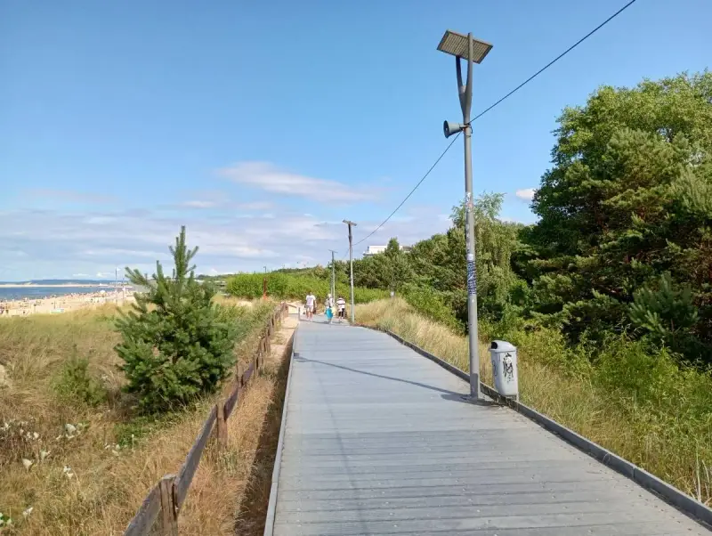 Spacer po promenadzie w Świnoujściu. Widok na plażę, morze i zielone drzewa. Atrakcje dla spacerowiczów.