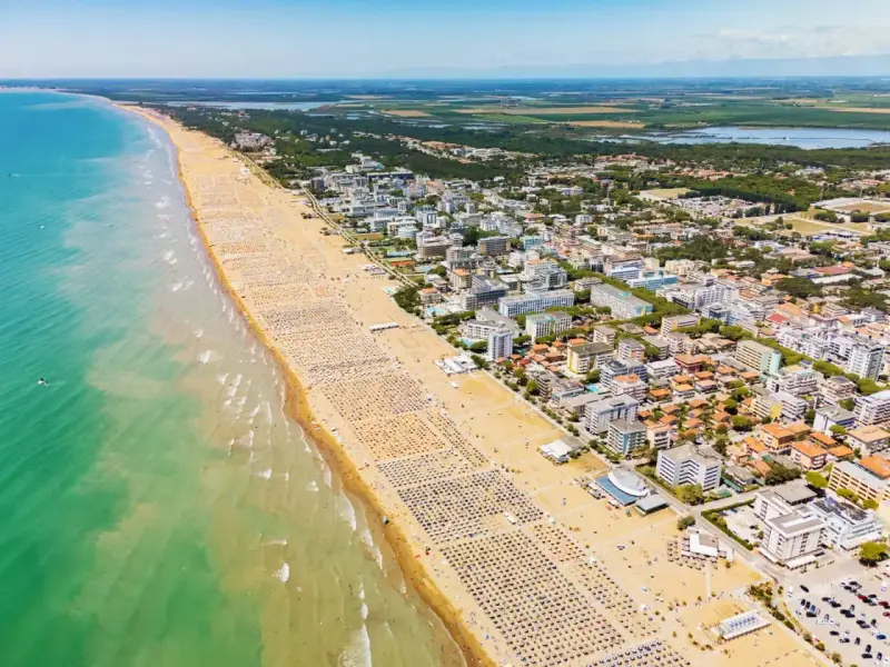 Słoneczna bibione plaża tętni życiem. Tysiące leżaków i parasoli tworzą barwny dywan na piasku, a turkusowe morze zaprasza do kąpieli.