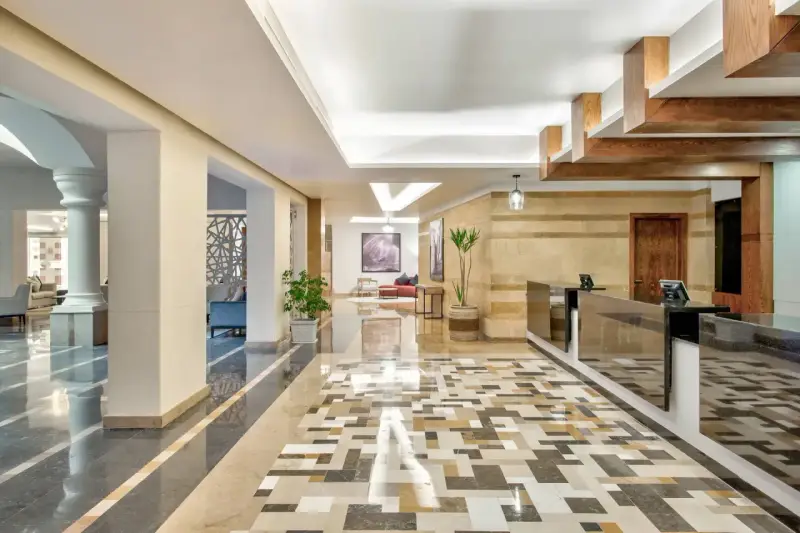 Eleganckie lobby hotelu Radisson z recepcją, ozdobnymi kolumnami i mozaikową podłogą. Radisson individuals witają tu gości.