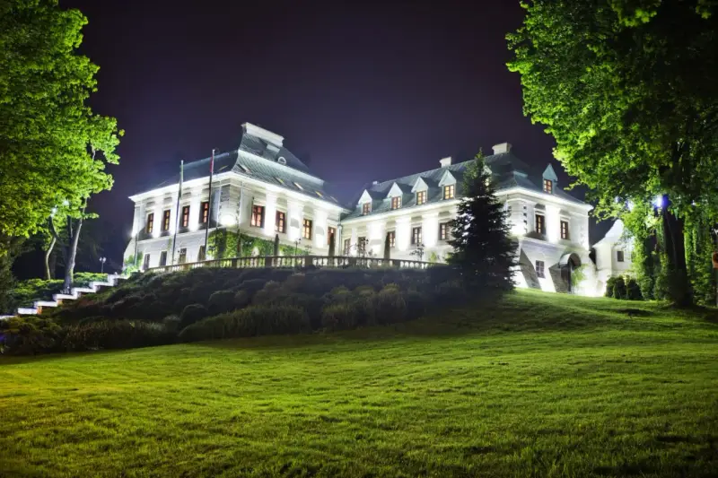 Elegancki hotel z atrakcjami dla dorosłych, nocą oświetlony, z pięknym ogrodem i zielonym trawnikiem.