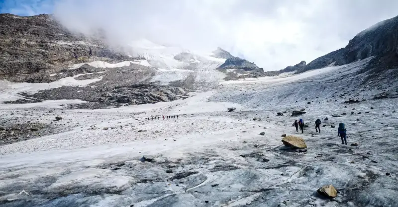 Grupa turystów wędruje po lodowcu w kierunku majestatycznego masywu Monte Rosa.