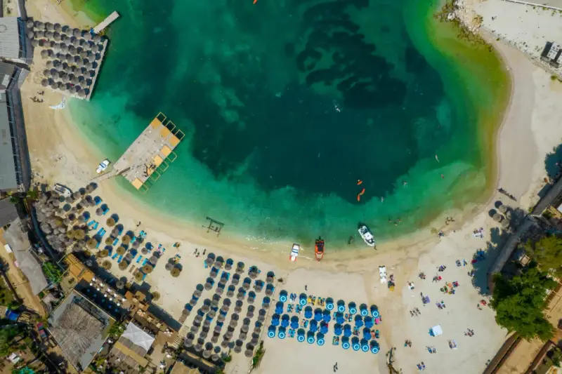 Widok z lotu ptaka na **Albania plaże** z turkusową wodą, leżakami i parasolami.
